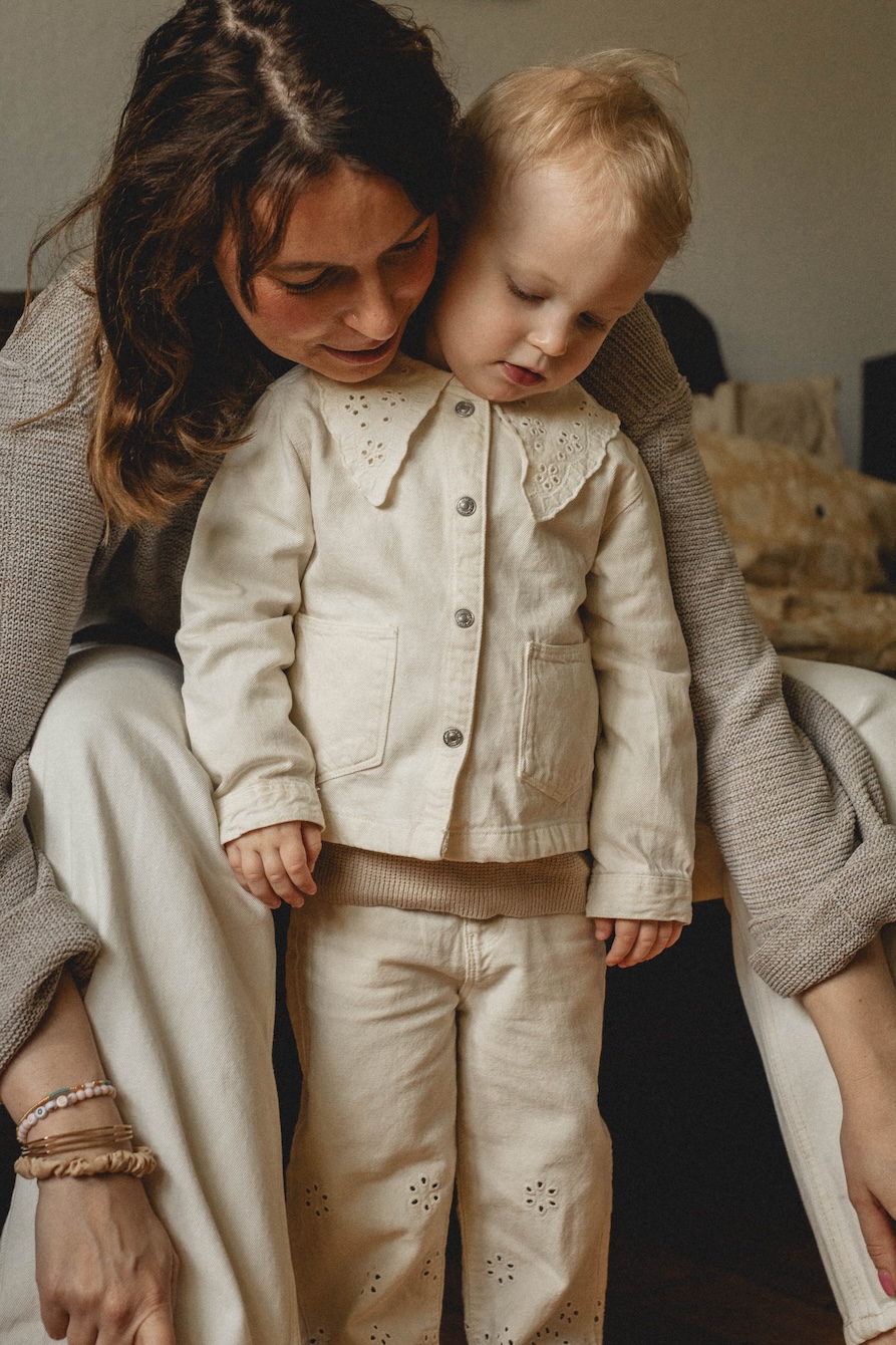 Mama und Kind ziehen sich zusammen die Schuhe an